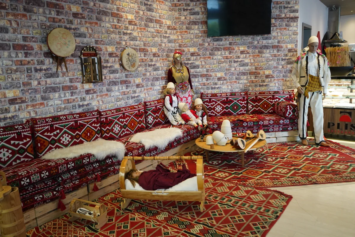 Eine Ecke, die mit Trachten und Möbeln aus dem Balkan geschmückt ist.